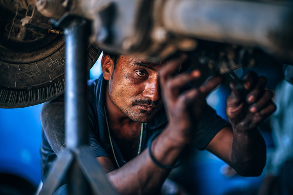 Mechanic inspecting the underside of a vehicle during a pre-trip inspection